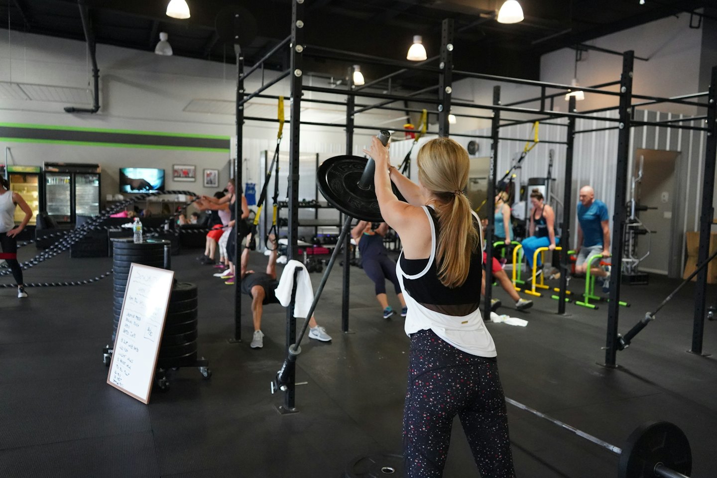 Adultos haciendo entrenamiento de intervalos de alta intensidad en un gimnasio moderno.